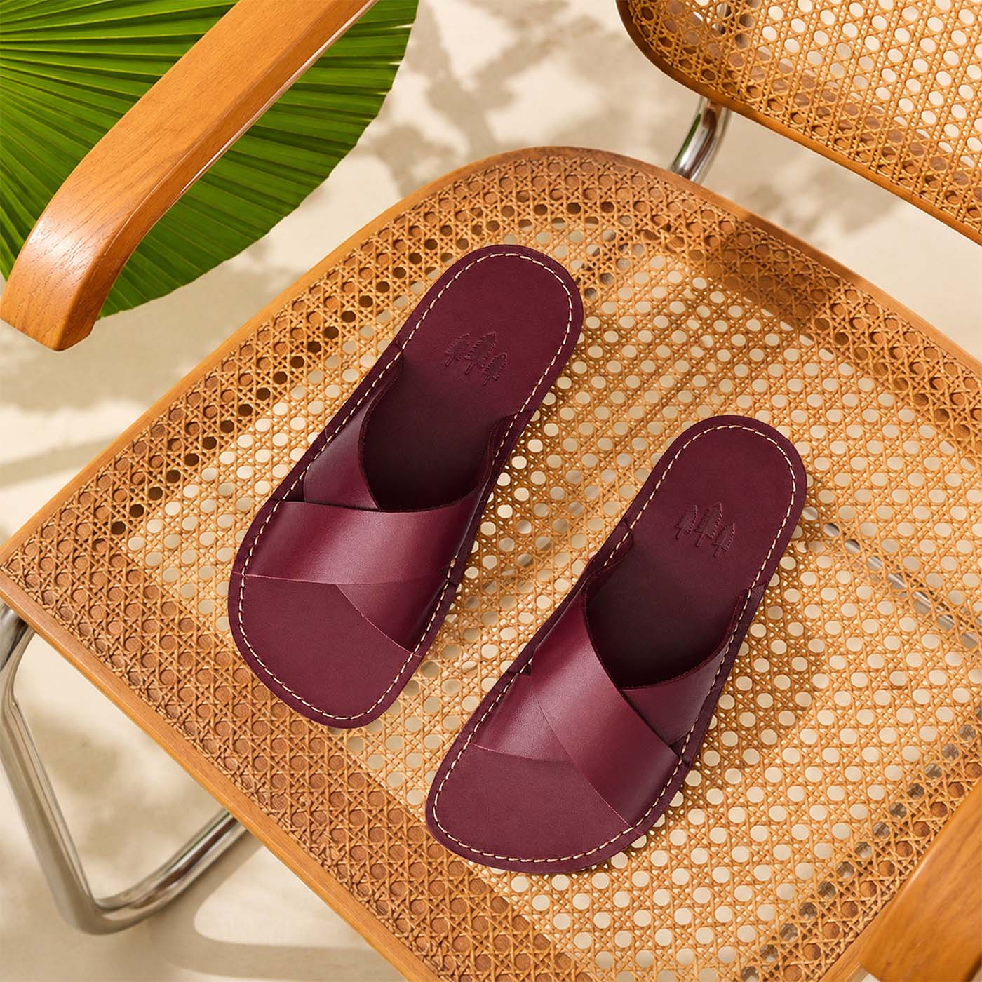 Marsala | Red wine colored-leather flat sandals with debossed Portland Leather trees logo set on a woven chair