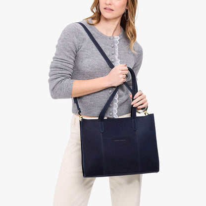Velvet Blue*East/West | Model holding structured wide tote bag with overlapping panels and crossbody strap
