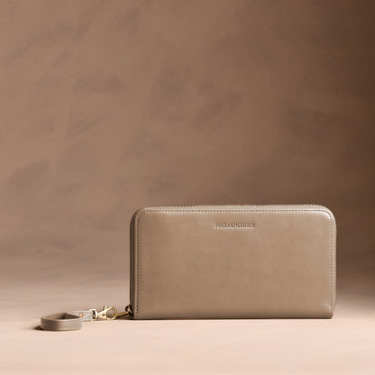 Satine | Full zip around wallet with a strap on a brown background