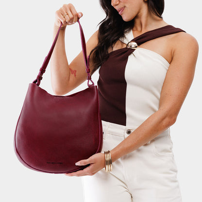 Orchid*Large | Woman wearing rounded shoulder bag with adjustable strap on a white background