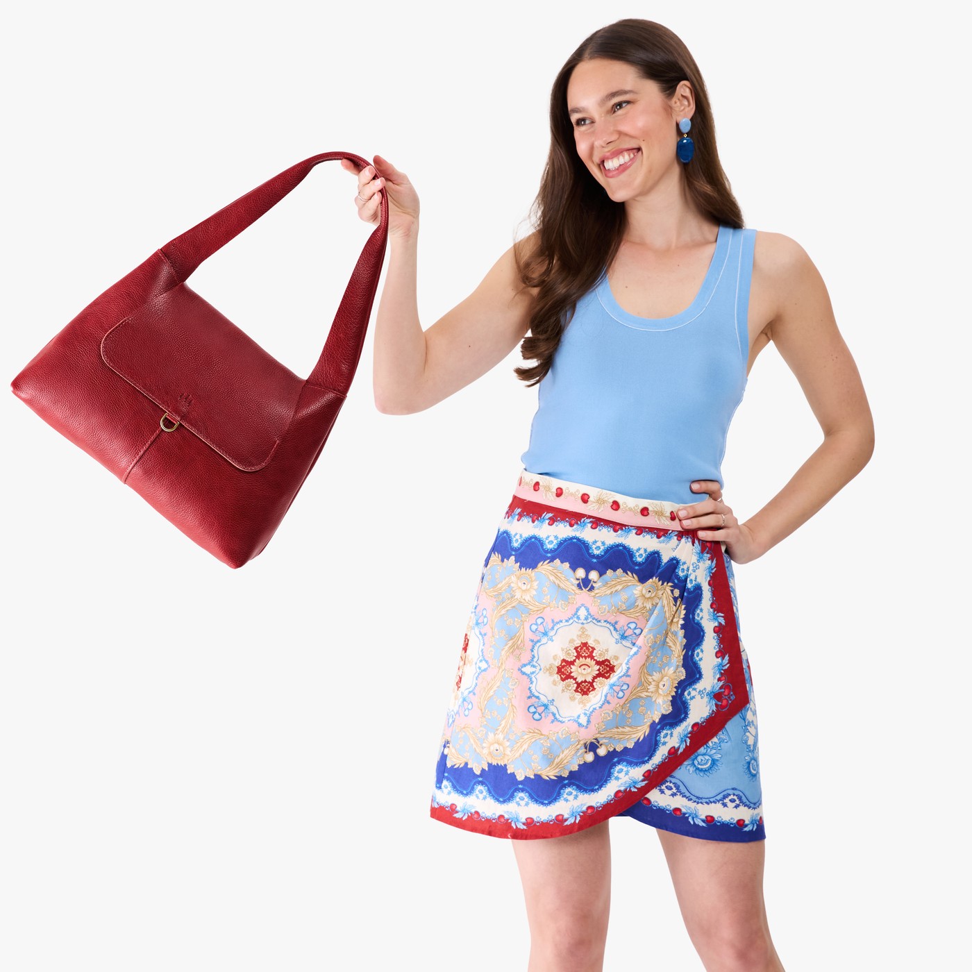 Chili Red*Medium | A model holding a slouchy triangle shaped shoulder bag with a flap
