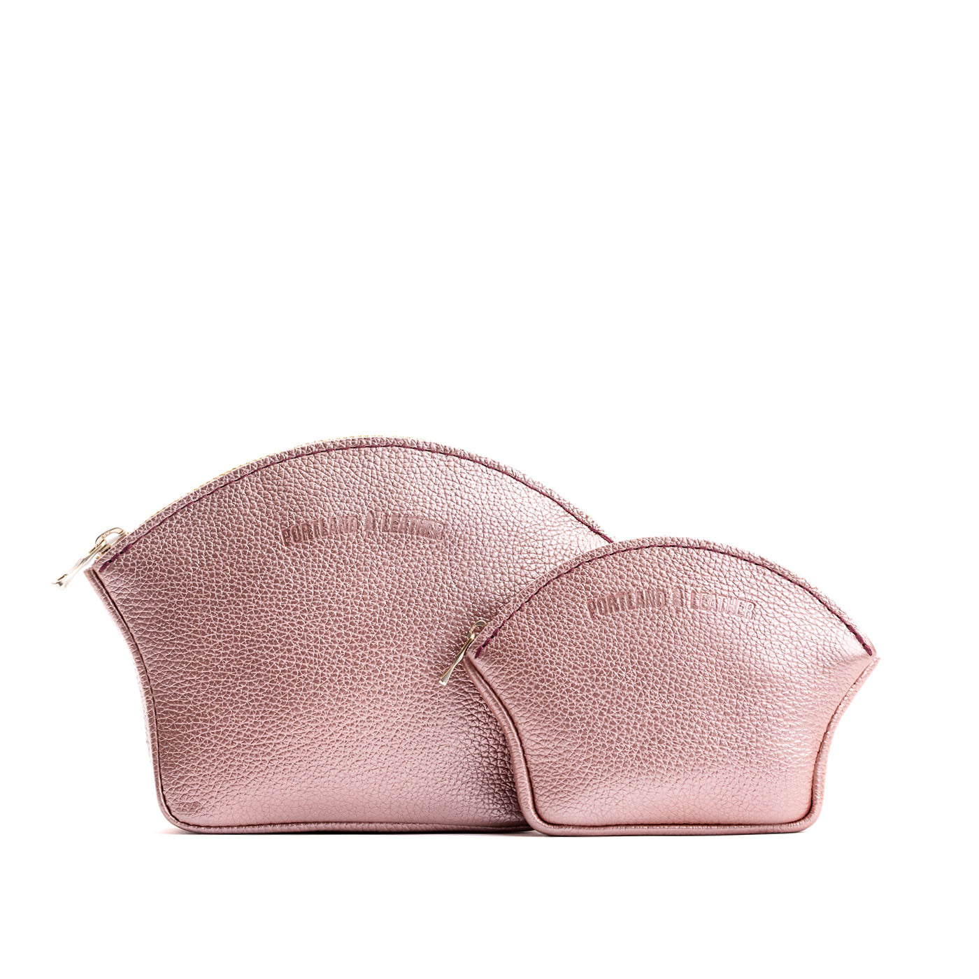 Supernova | Comparison shot of small and large seashell shaped leather makeup bags with curved top zipper and flat bottom