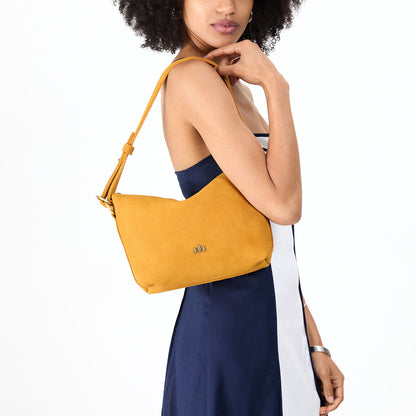 Dijon*Small | Model holding a Slouchy Shoulder Bag that has a zipper opening and three metal tree emblems