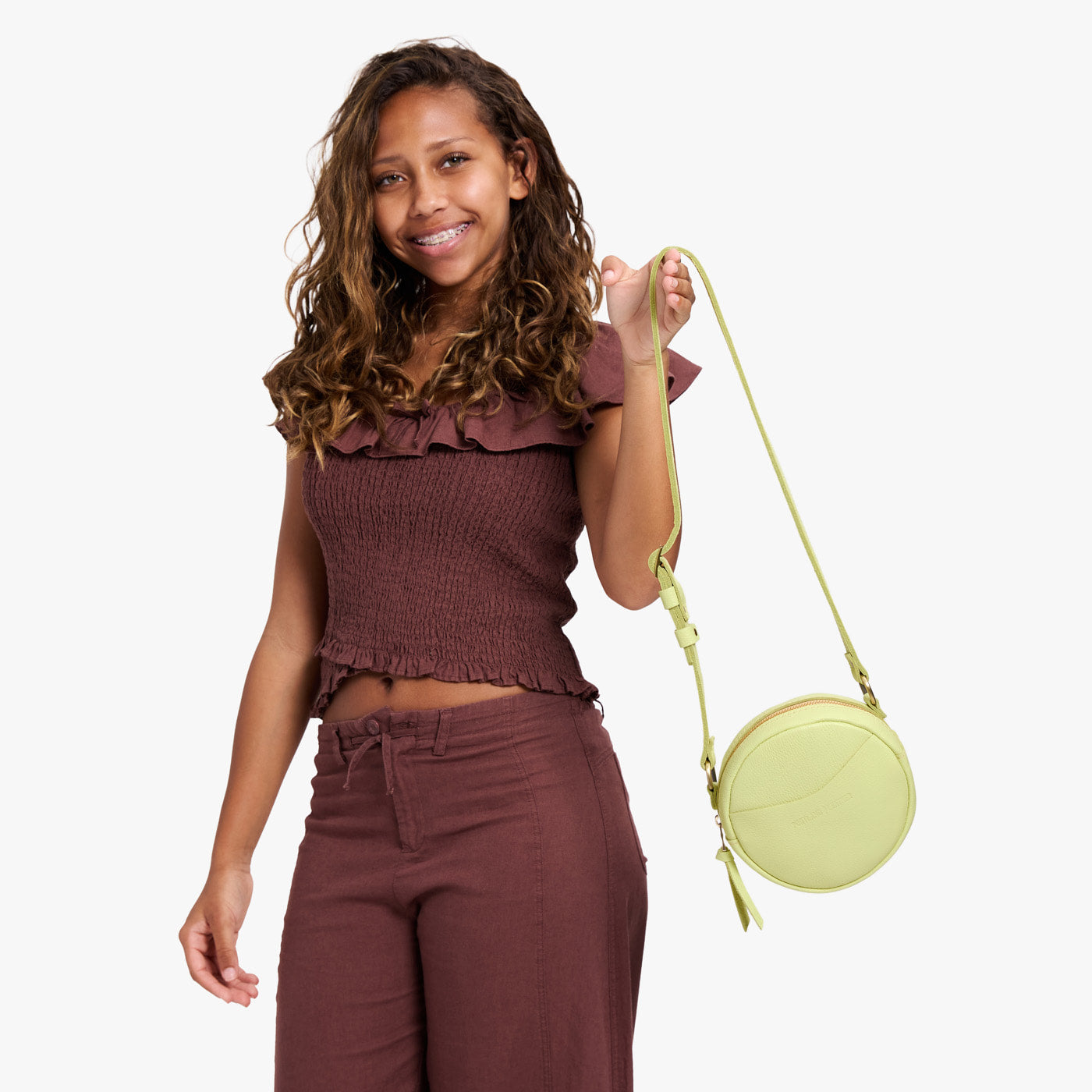 Shadow Lime | Model holding a circle shaped crossbody bag with top zipper and gold accents